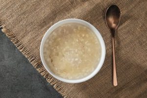 A bowl of broth with a gold spoon to the right