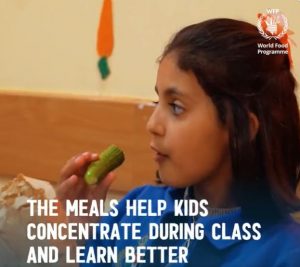 A child with dark hair eats food white text on the image says the meals help kids concentrate during class and learn better