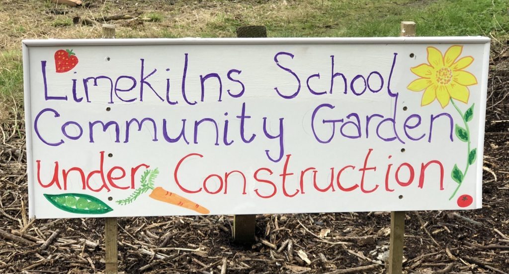 A colourful handwritten sign with text saying Limekilns School Community Garden under Construction